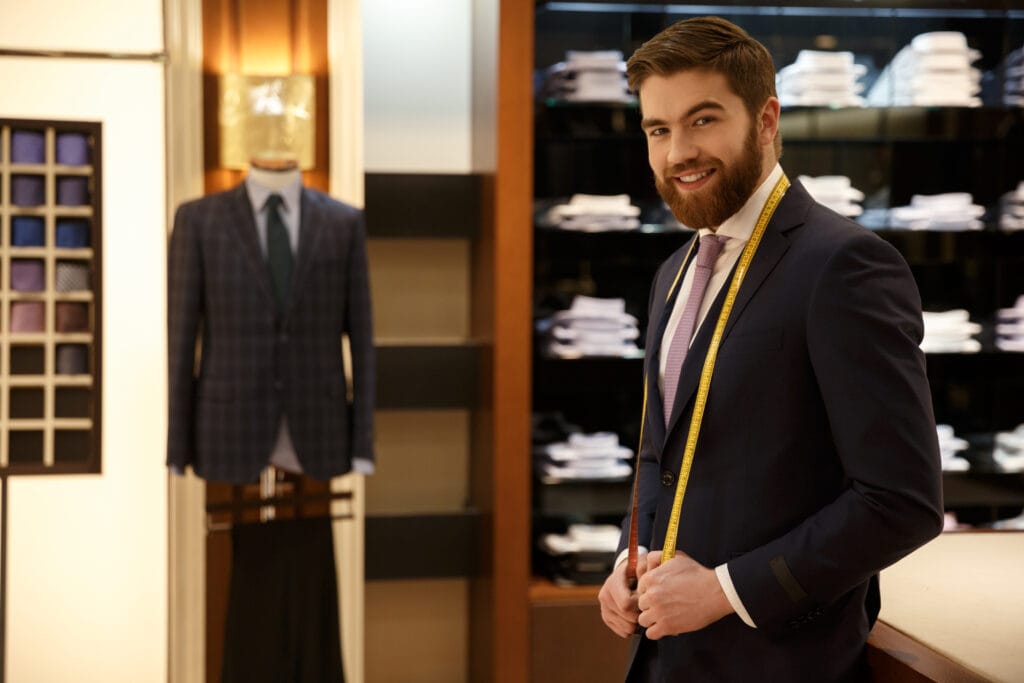Smiling man standing in wardrobe with measure tape